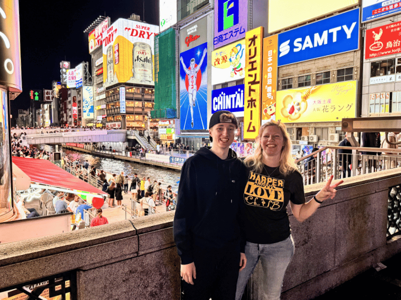 Mutter und Sohn vor bunter Leuchtreklame in Osaka