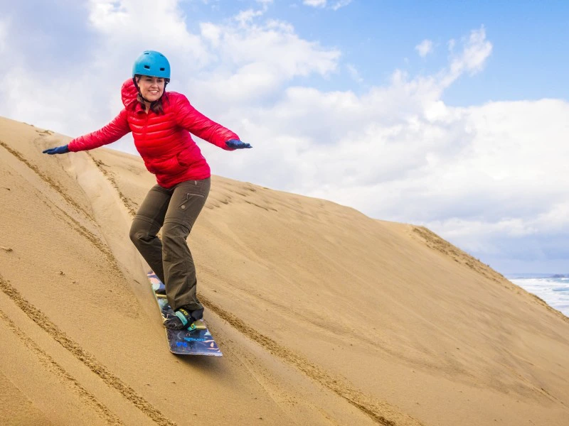 Frau beim Sandboarding in den Dünen von Tottori, Japan