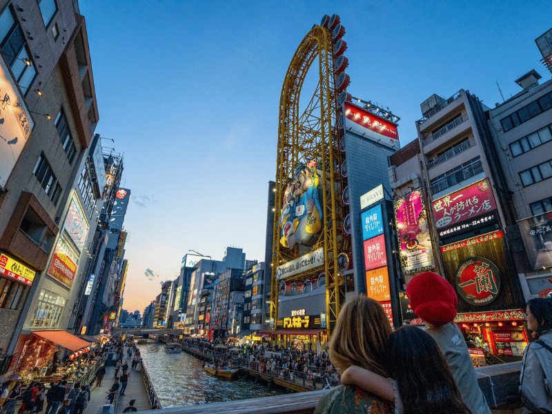 Mutter und Sohn vor bunter Leuchtreklame in Osaka