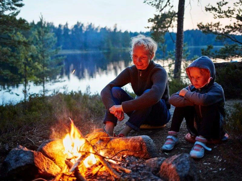 Mutter mit jungen Sohn am Lagerfeuer in Schweden