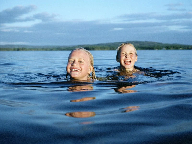Kinder schwimmen in einem See in Schweden