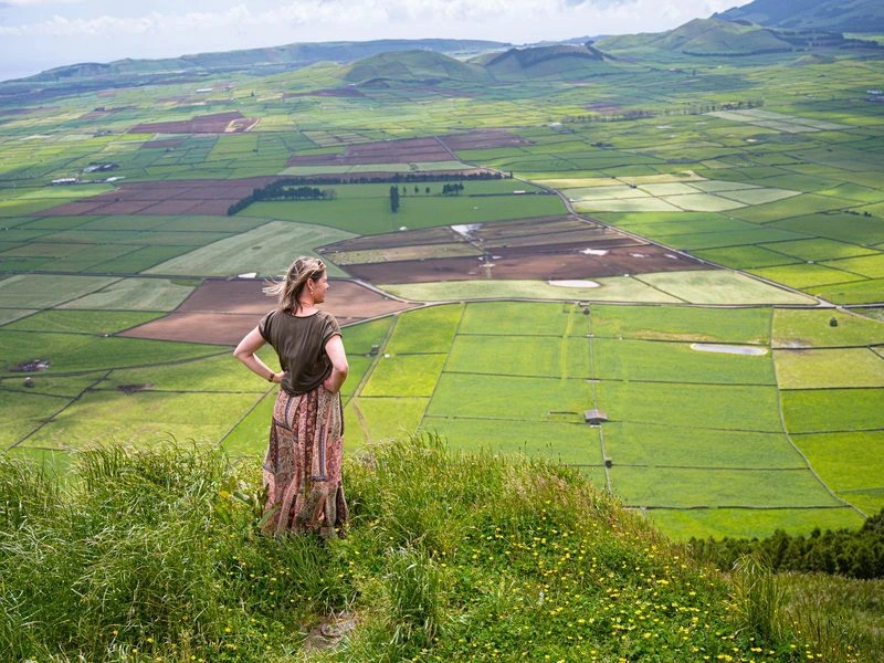 Frau schaut auf die grüne Landschaft auf den Azoren