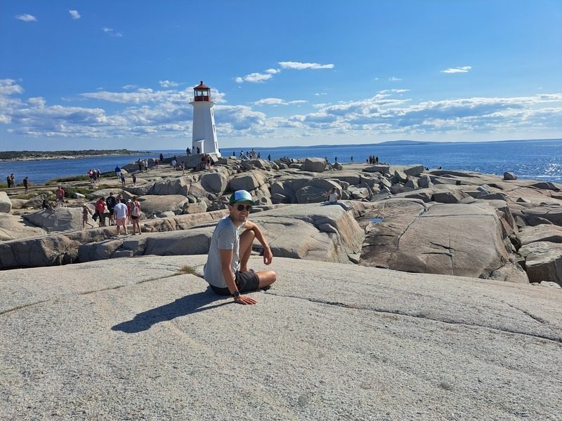 Mann auf einem Felsen mit Leuchtturm im Hintergrund