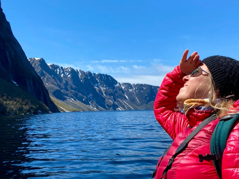 Reisende schaut vom Boot die Felsen an im Gros Morne Nationalpark in Neufundland in Kanada