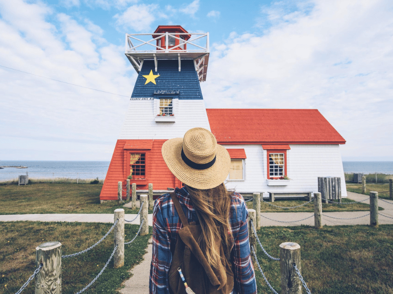 Reisende schaut einen Leuchtturm an der Küste der Akadier in Kanada an