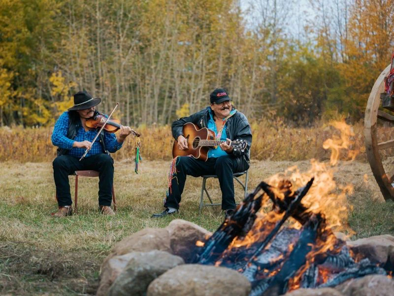 Métis mit Gitarre am Lagerfeuer