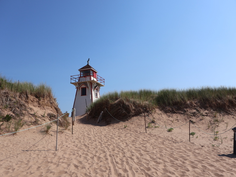 Reisende am Strand auf Prince Edward Island mit roten Klippen