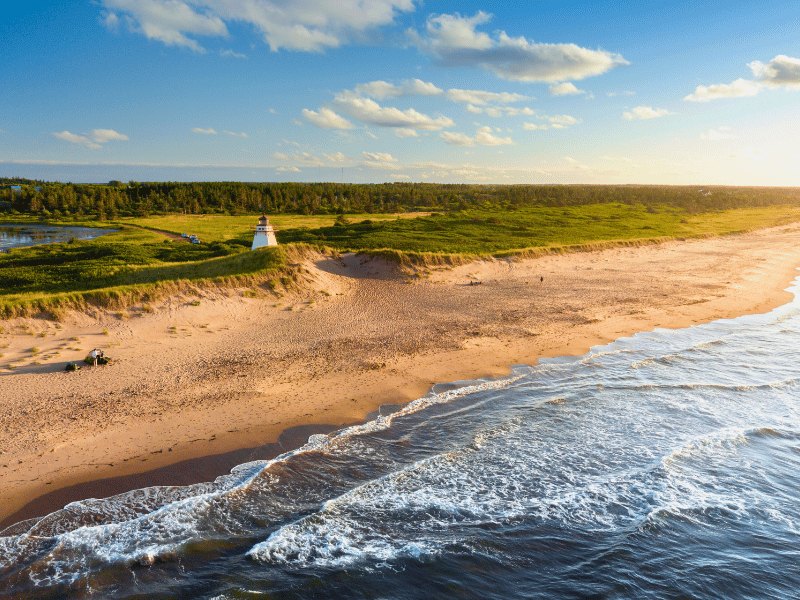 Leuchtturm an Strand auf Prince Edward Island mit Dünen und Meer