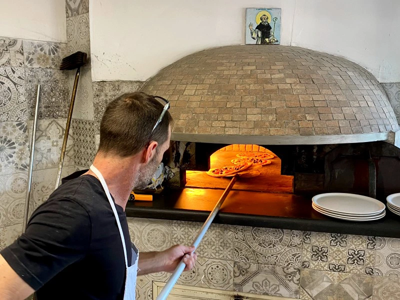 Mann schiebt Pizza in den Ofen