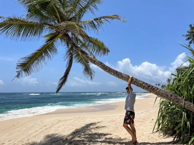 Tourist posiert an einer Palme am Strand von Kalpitiya in Sri Lanka