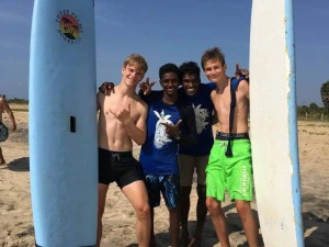Jungs mit Einheimischen mit Surfbrettern am Strand in Sri Lanka