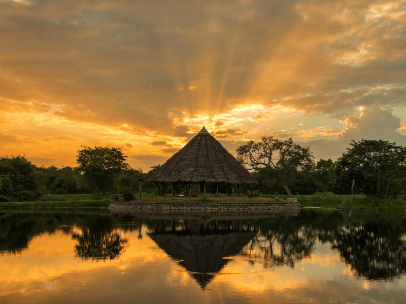 Strohbedeckter Pavillon an einen See bei Sonnenuntergang in Sri Lanka