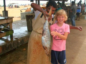 Junge und Fischer mit einem Fisch auf dem Markt in Negombo