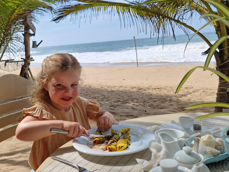Kleines Mädchen beim Frühstück am Strand in Sri Lanka