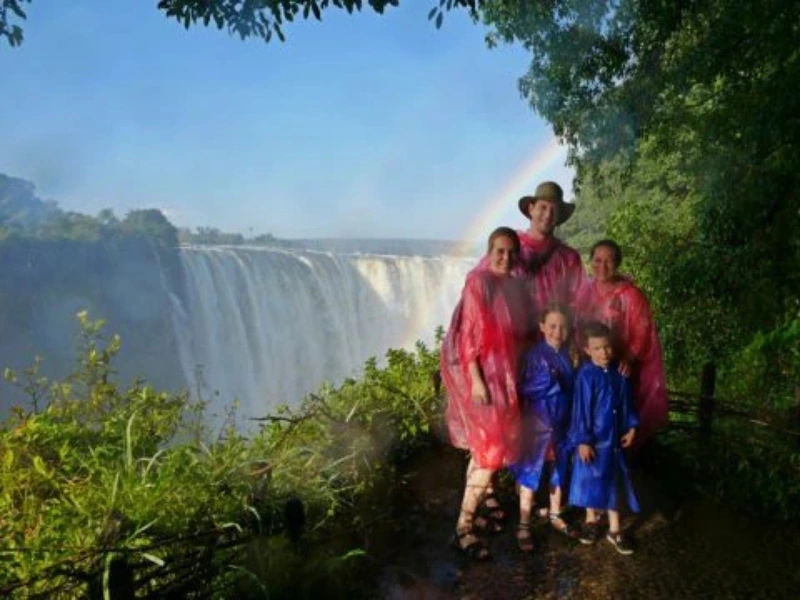 Namibia Botswana Familienreise Victoria Falls reisende Familie in Regenponchos vor dem Wasserfall