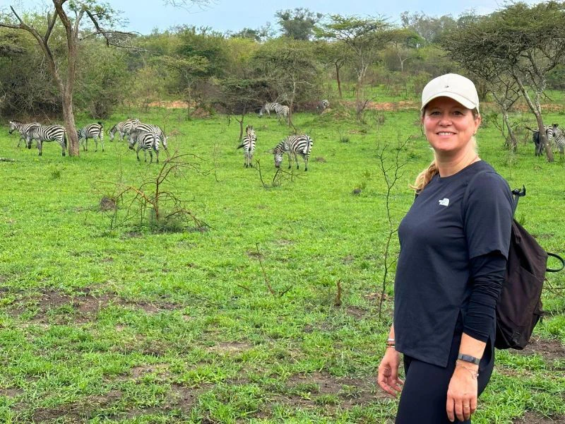 Uganda Lake Mburo Wandersafari Reisende posiert vor einer Herde Zebras