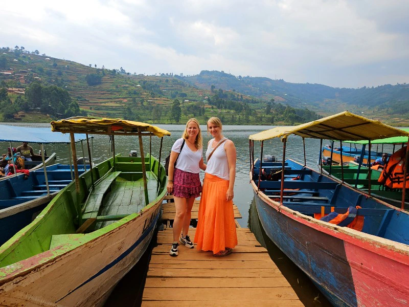 Uganda Lake Bunyonyi Reisende stehen auf einem Steeg zwischen bunten Booten