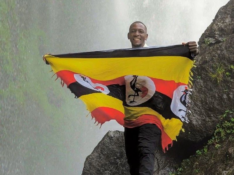 Uganda Guide posiert vorm Wasserfall
