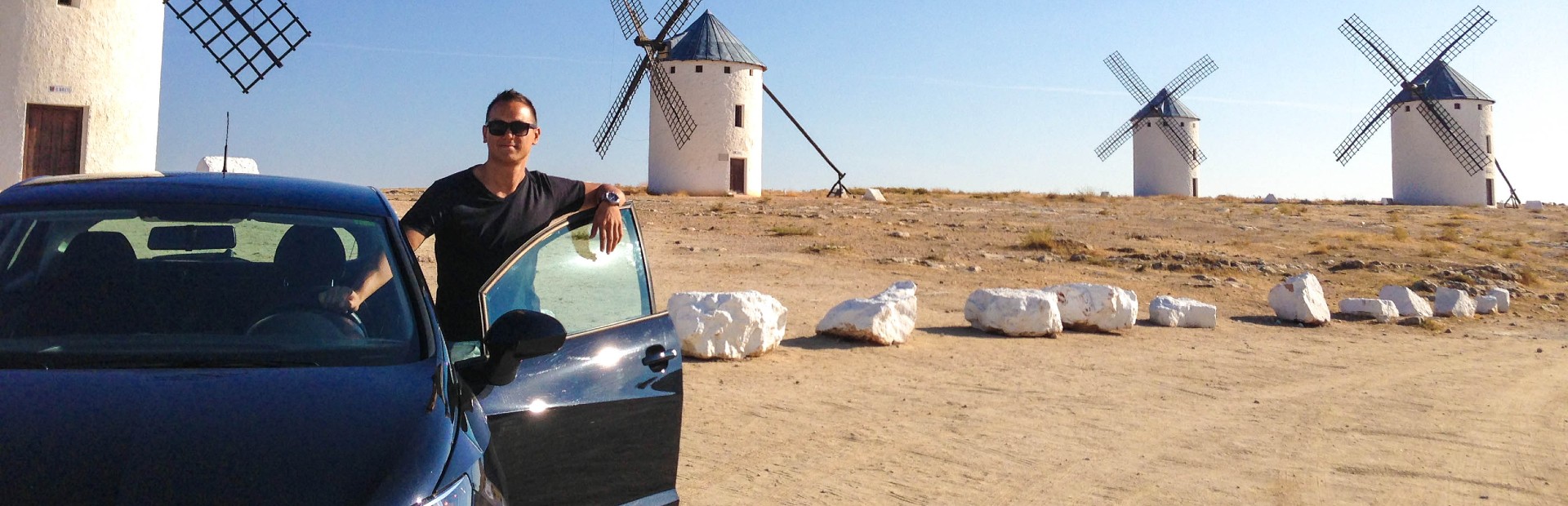 Mann am Auto vor Windmühle