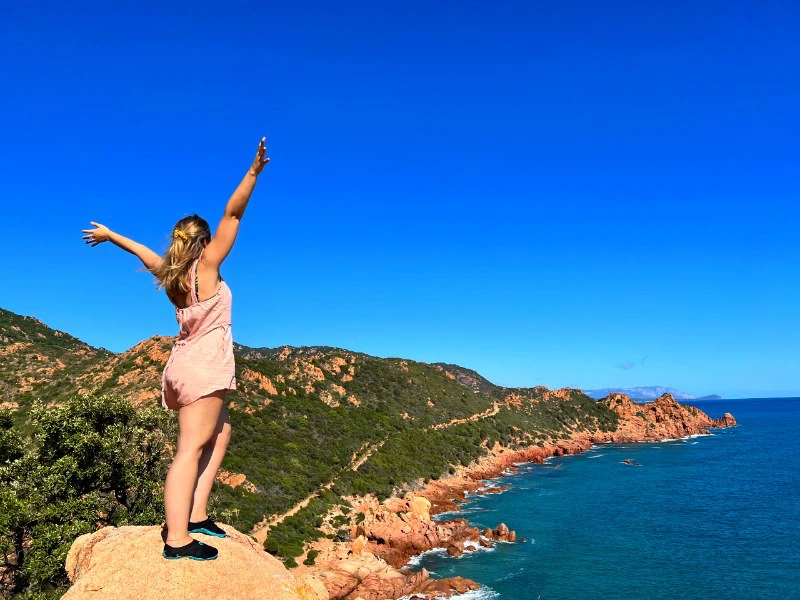Frau schaut auf Küste in Sardinien