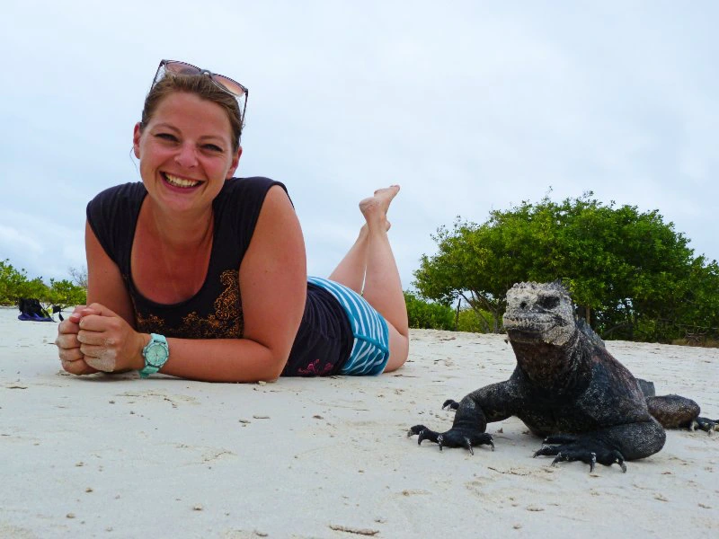 Reisende liegt neben einer Echse am Strand auf den Galapagos Inseln in Ecuador