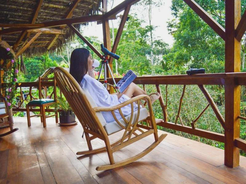 Frau liest in Schaukelstuhl auf der Veranda