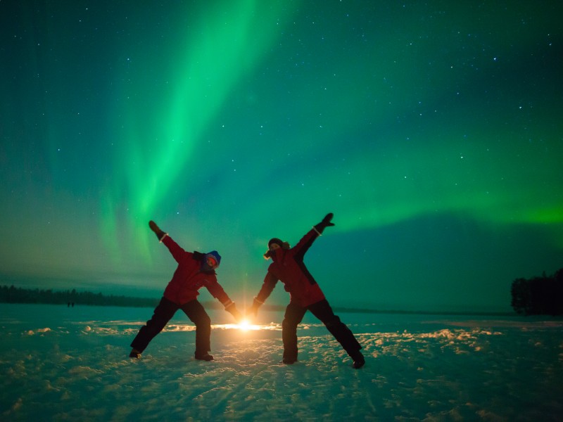 Reisende im Schnee unter dem Nordlicht in Finnland