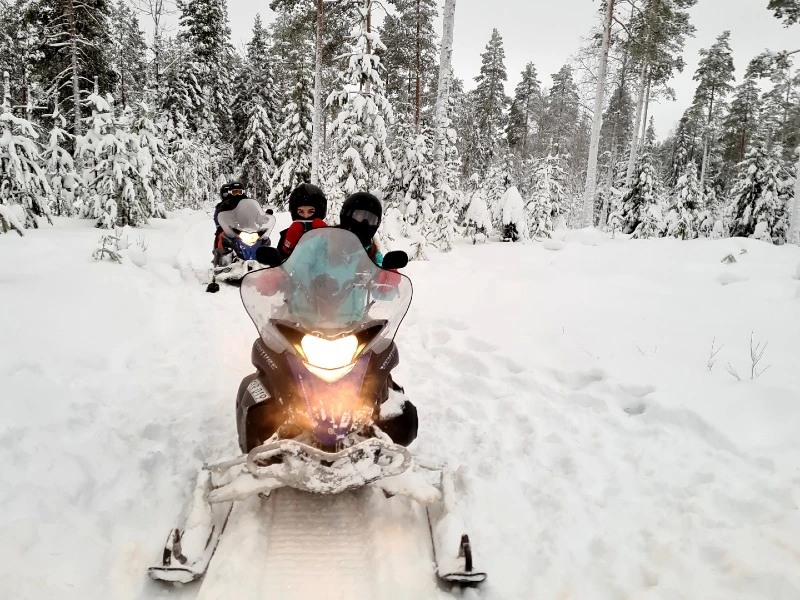 Familie bei einer Schneemobiltour in Lappland