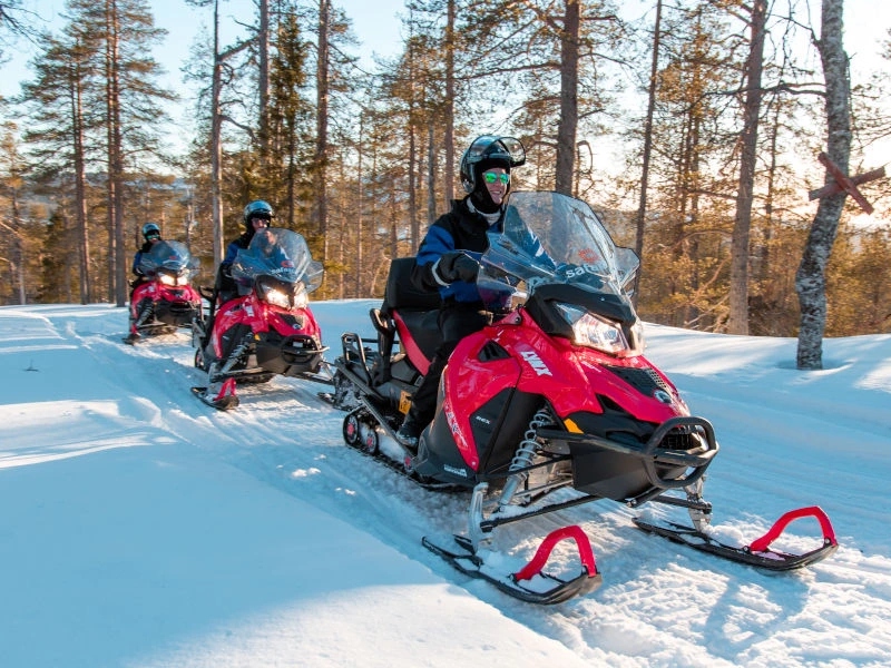 Reisende bei einer Schneemobiltour in Lappland