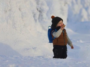 Kind im Schnee mit Zimtschnecke
