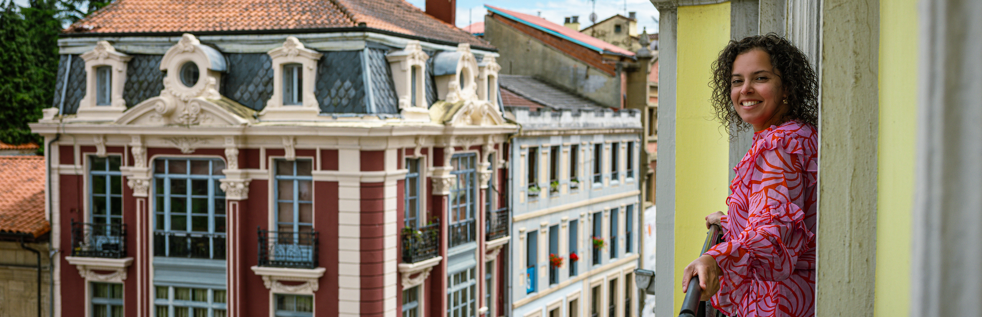 Frau blickt aus dem Fenster eines Hotels in Oviedo, Spanien