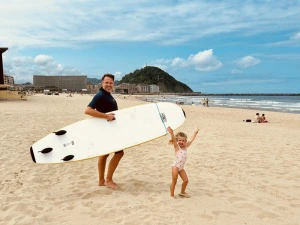 Vater mit Tochter in San Sebastian am Strand mit Surfboard, Spanien