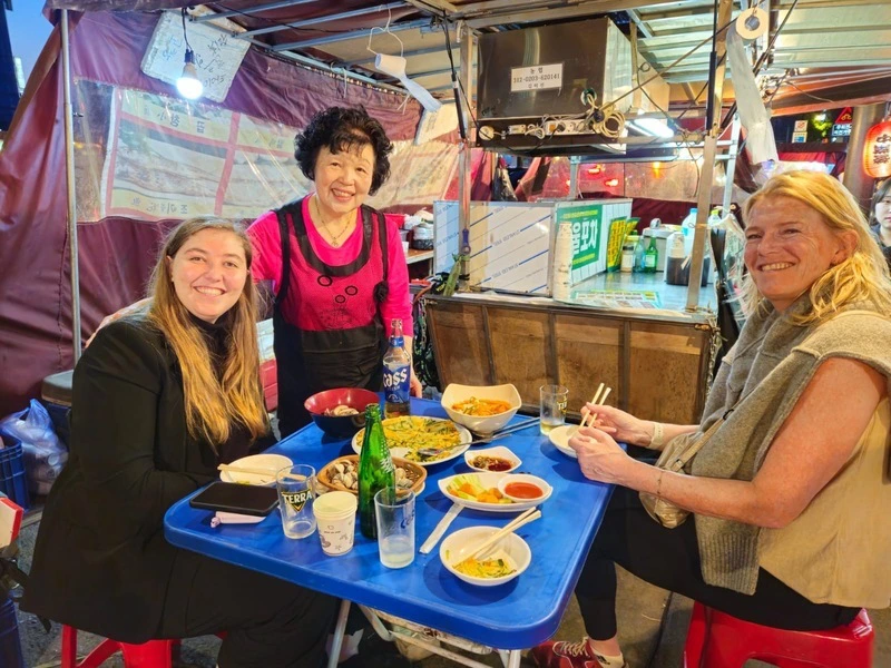 Touristinnen mit der Köchin vom Street Food in Seoul, Südkorea