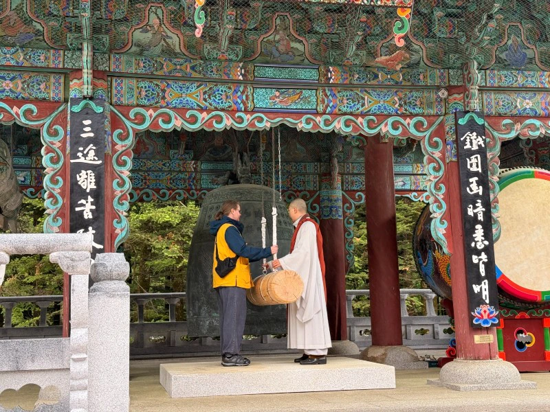 Tourist mit Mönch an einem Gong im Tempel in Woljeongsa in Südkorea
