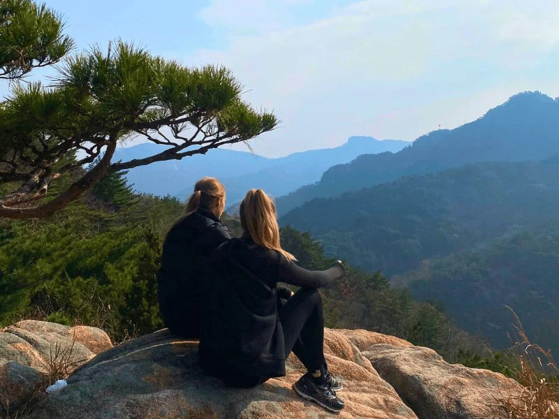 Zwei Reisende schauen von einem Aussichtspunkt auf die weite Landschaft in Südkorea
