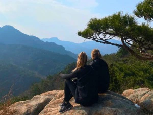 Zwei Reisende schauen von einem Aussichtspunkt auf die weite Landschaft in Südkorea